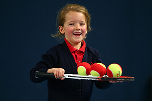 Young child holding racket and tennis balls